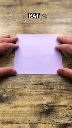 two hands holding an empty piece of paper on top of a wooden table with the words rat