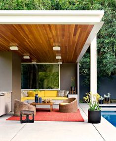 an outdoor living area with couches and tables next to a swimming pool in the background