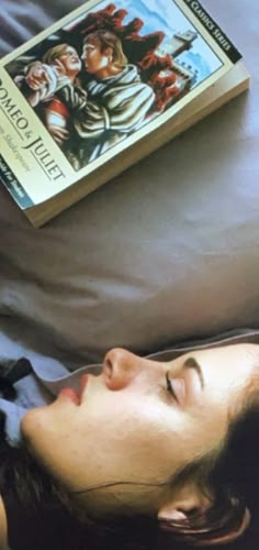 a woman laying in bed next to a book