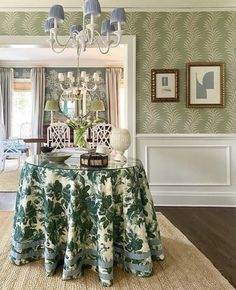 a dining room table covered with a blue and white cloth under a chandelier