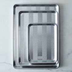 three metal trays sitting on top of a marble counter