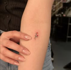 a woman's arm with a tiny red flower on the tip of her left arm