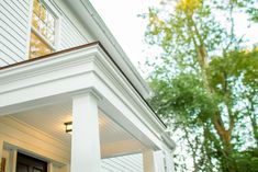 the front porch of a house with white siding and wood trimmings on it