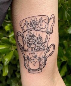 a tattoo on the leg of a woman with flowers in a tea cup and saucer