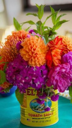 an arrangement of flowers in a bucket on a table