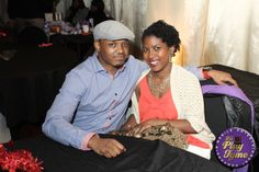 a man and woman sitting next to each other in front of a table with decorations