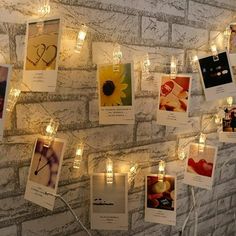 there are many pictures on the wall with lights strung from them and some cards attached to it