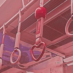 red heart shaped handles hang from the ceiling in a subway car with pink and purple background