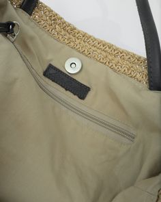 a close up of a bag with a metal button on the side and a woven handle