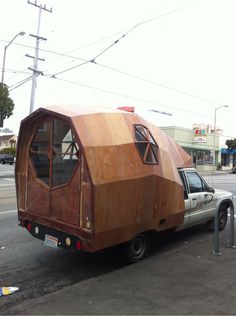 a car with a wooden trailer attached to it's back parked in front of a building