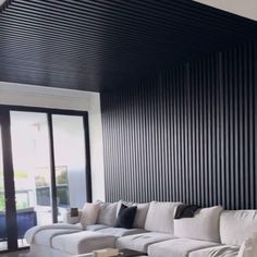 a living room filled with white furniture next to a sliding glass door covered in black slats