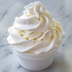 a white cup filled with whipped cream on top of a table