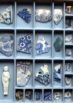 an assortment of blue and white ceramic items in a tray with dividers on the wall