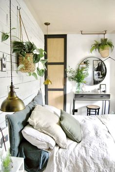 a bedroom with white walls and plants hanging from the ceiling, along with a bed