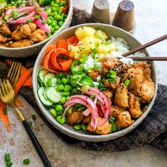 two bowls filled with chicken and vegetables next to utensils on top of a table