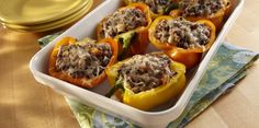 several stuffed peppers in a white dish on a wooden table