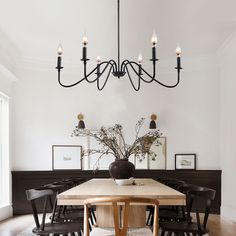 a dining room table with chairs and a chandelier hanging from it's ceiling