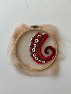 an embroidery hoop with a red and white design on it