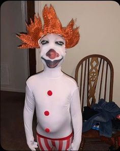 a man dressed as a clown standing in front of a dining room table and chair