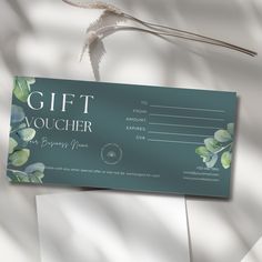 a gift voucher card sitting on top of some white paper with leaves and flowers