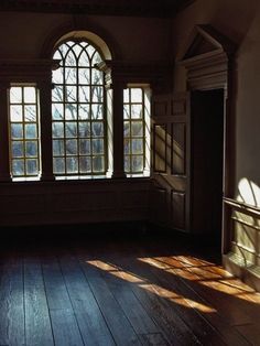 an empty room with wooden floors and arched windows