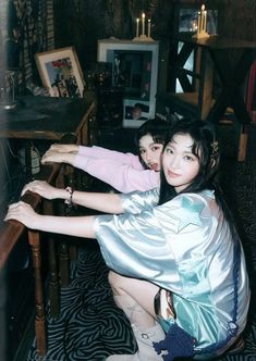 two young women sitting at a table with their arms around each other, both wearing boots