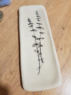 a white plate sitting on top of a wooden table next to a glass vase with flowers in it