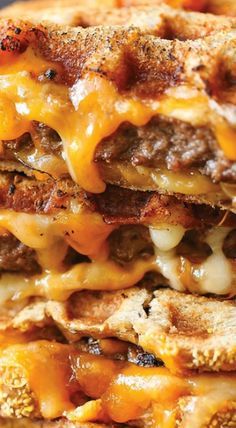 two grilled cheeseburger sandwiches stacked on top of each other with melted cheese