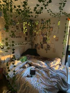 an unmade bed with lots of plants growing on the wall above it, in a bedroom