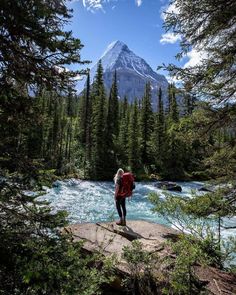 a woman standing on a rock looking at a mountain