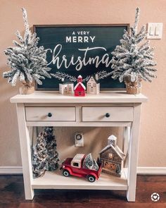 a white table with christmas decorations on it and a sign in the background that says merry christmas