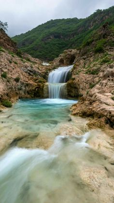 a small waterfall in the middle of a rocky area with water running down it's sides