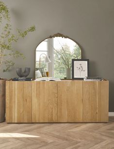 a living room with a large wooden cabinet and mirror on the wall next to a potted plant