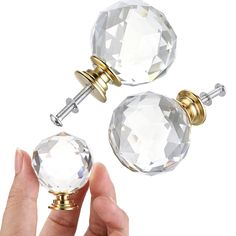 a person holding two crystal knobs in their left hand and the top one is gold