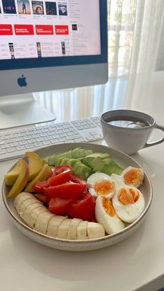 a white plate topped with sliced up fruit and veggies next to a computer