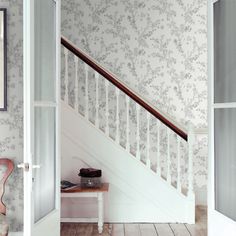 an open door leading to a stairway with wallpaper on the walls and wooden flooring