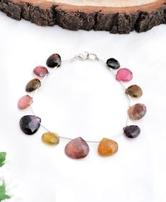 a bracelet with multicolored stones on it sitting next to a piece of wood