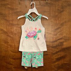 Cute 2 Piece Ocean-Themed Short Set From Tommy Bahama In Girls Size S (5/6). Top Measurements: 22" Chest & Waist | 18" Length From Shoulder. Shorts: 20-24" Waist | 10 1/2" Length | 5 1/2" Inseam. Girls Set Includes Two Pieces: A Tank Top And Shorts. Tank Top Is White With A Sea Turtle/Ocean Graphic On The Front Embellished With Sequins And Glitter. Sleeveless: Straps Are "Braided" And Criss-Cross In The Back. Soft And Stretchy Cotton Knit. Matching Shorts Are Green With An Ocean Print On Them. E Playful Tank Top For Beach, Ocean Graphic, Tank Top And Shorts, Turtle Tank, Top Measurements, Ocean Print, Cotton Tank Top, Short Set, Knit Shorts