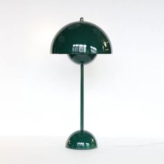 a green table lamp sitting on top of a white floor