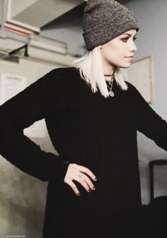 a woman with white hair wearing a black dress and a gray beanie is posing for the camera