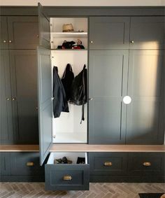 an open closet with several coats hanging on the doors and shoes in the bottom drawer