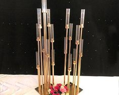 there is a vase with flowers in it on the table next to some sticks and candles