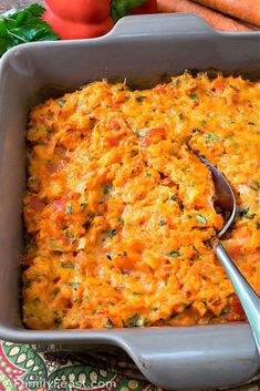 a casserole dish with carrots, tomatoes and parsley on the side