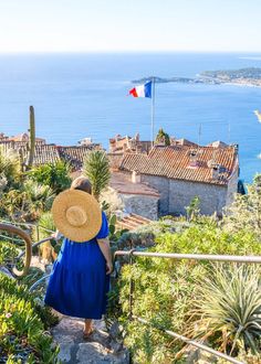 a woman in a blue dress and straw hat walking up stairs to the beach with an italian flag