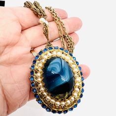 Gorgeous Vintage Signed WEST GERMANY Blue Slag Glass Faux Pearl & Rhinestone Necklace. Ornate gilt filigree metal set with blue slag glass stone and surrounded by faux pearls and blue rhinestones. Signed on jump ring. In excellent vintage condition with minimal age appropriate wear. Pendant measures 2 3/4 inches long from the heart and is 1 5/8 inches wide. Total length is 24 inches long. Clasp secure. Blue Jeweled Metal Jewelry, Antique Blue Metal Jewelry, Blue Cabochon Metal Jewelry, Blue Metal Cabochon Jewelry, Blue Victorian Jewelry For Collectible, Vintage Blue Necklace With Pearl Pendant, Blue Victorian Metal Jewelry, Vintage Blue Necklaces With Polished Beads, Antique Blue Multi-stone Jewelry