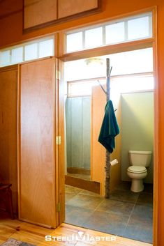 an open bathroom door with a towel hanging from it's pole in front of the toilet