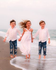 three children are running on the beach together