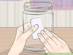 two hands holding a card in front of a jar