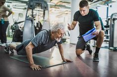 an older man is doing push ups on a mat in the gym with his trainer