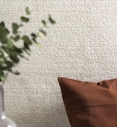 a brown pillow sitting on top of a wooden table next to a vase filled with flowers